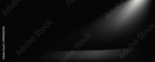 A stark, textured black surface is illuminated by a single, powerful beam of white light originating from the upper left, casting a dramatic spotlight.