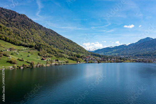 Lake Zug panoramic view - calm blue water, rolling green foothills and Alpine village in Central Switzerland