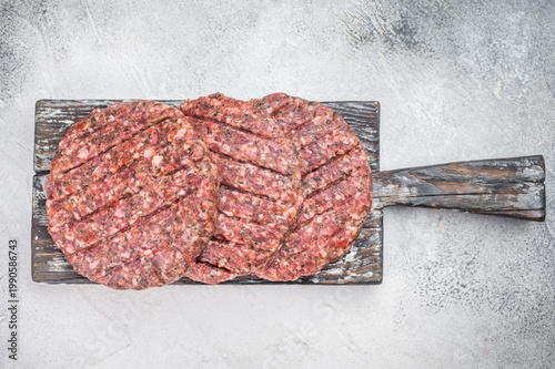 Raw mixed meat patties made from beef and lamb with herbs and salt. Light stone background flat lay with copy space for menu design.