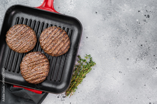 Cooked mixed meat patties made from beef and lamb in grill pan. Light stone background with copy space for food design.