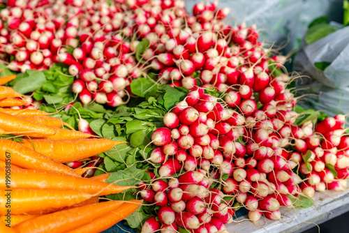 Fresh radishes and carrots for sale at a market stall