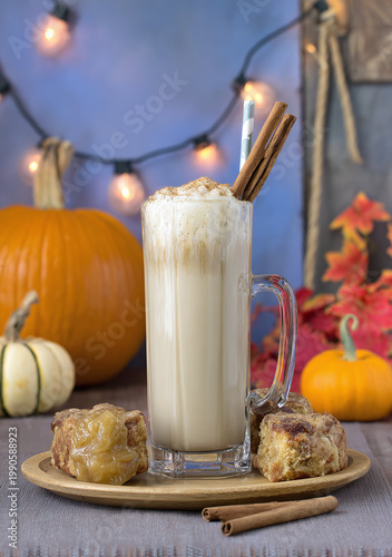 Autumn-inspired beverage with a creamy foam topping, served with pumpkin treats and decorative fall elements.