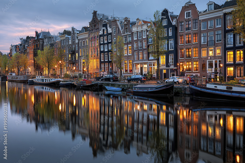 Fototapeta premium Panoramic canal cityscape at blue hour with traditional narrow houses and boats reflecting on calm water, creating peaceful and charming urban scene