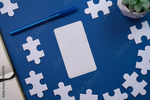 Blank white card framed by white puzzle pieces and a blue pen