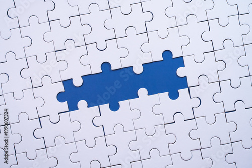 White jigsaw puzzle with missing blue pieces symbolizing incomplete solution