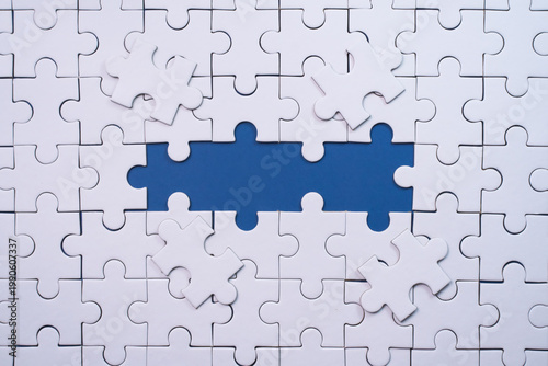 White jigsaw puzzle with a single missing blue piece revealed