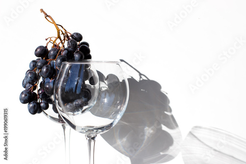 Two wine glasses on a white background. A glass with grapes and an empty glass. Winemaking. Horizontal photo with space for text