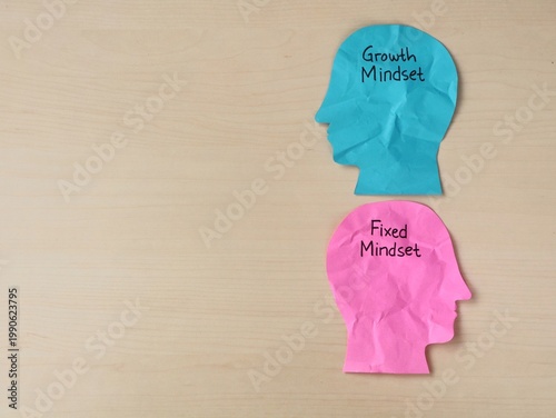 Fixed vs growth mindset concept with paper head silhouettes on wooden background. Perfect for educational, coaching, business development, and mental health themes