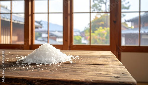 Pile of Coarse Salt Crystals on a Rustic Wooden Table by a Window.