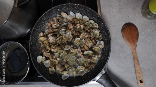 Clams sizzle as they cook in a cozy kitchen on a sunny afternoon