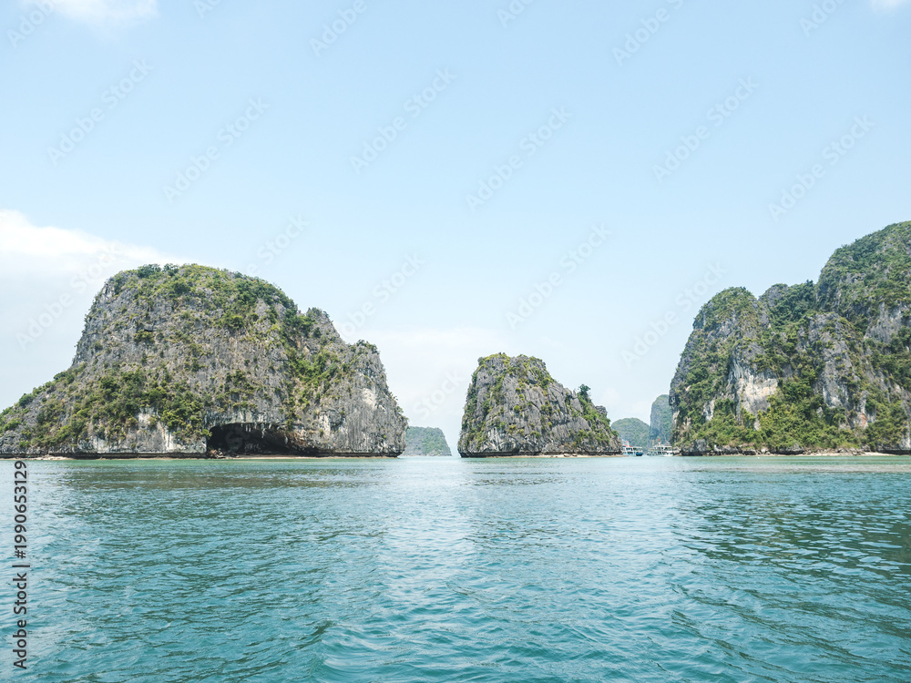 Naklejka premium Stunning views of Ha Long Bay. Symbolizes serene travel, adventure, and Vietnam's natural beauty. Ideal for tourism, vacation and scenic content. Lush greenery and calm waters create a peaceful escape