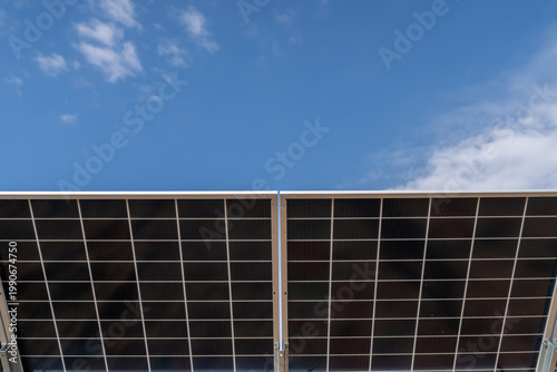 Fotografia Ground mounted PV panels seen against blue sky with detailed cell pattern and me