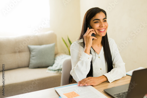 Female lawyer talking on smartphone managing business calls from home office, working and smiling in a professional setting