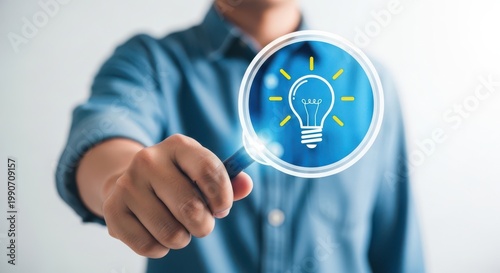Person holding a magnifying glass over a light bulb idea icon with lightbulb magnifying innovation