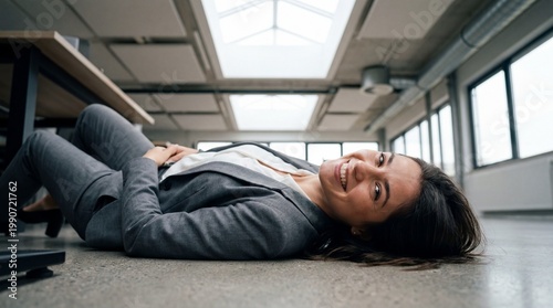 Smiling woman in business suit lying on the floor of a modern office