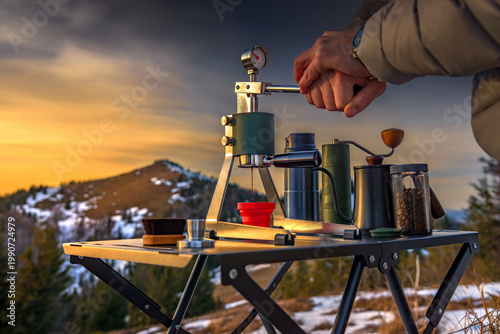 Man brewing espresso with manual lever coffee maker in mountains. Outdoor barista travel lifestyle