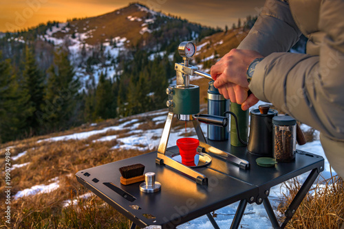 Man brewing espresso with manual lever coffee maker in mountains. Outdoor barista travel lifestyle