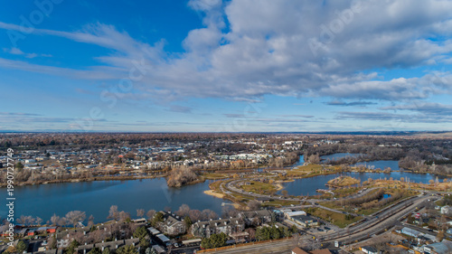 Wide Aerial Panoramic of Suburban City with Multiple Ponds and Water Features Under Dramatic Blue Sky with Clouds