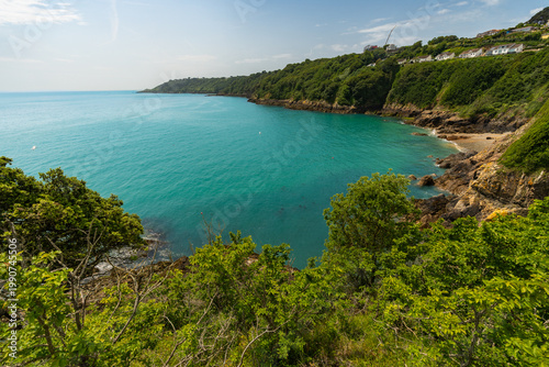Scenic coastal landscape of Guernsey, Channel Islands, with turquoise sea, rugged cliffs and lush greenery.