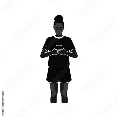 Silhouette of young woman in t-shirt and shorts using smartphone with dark hair in bun standing in front of white background.