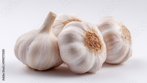 Four whole, unpeeled bulbs of fresh garlic with papery white skin, on a white background