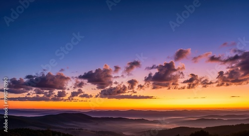 A stunning sunset with dramatic clouds in orange, pink, and purple hues. Rolling hills and mountains create silhouettes as the sun dips below the horizon. Perfect for nature backgrounds.