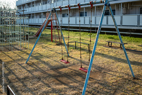 Konstfotografi Empty swings and jungle gym in an old public housing playground in the evening