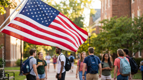 Group of diverse college students walking on campus with an American flag waving in the foreground, surrounded by trees and brick buildings, for education and university content, student lifestyle