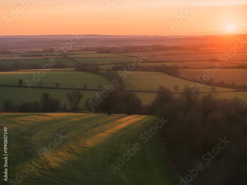 Aerial view of rolling green fields and hedgerows at sunset
