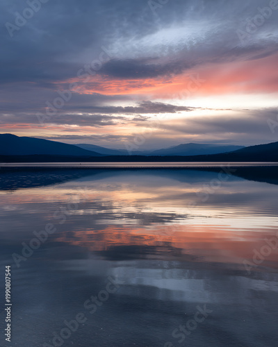 Sunset reflected on a calm lake with distant mountains with no people
