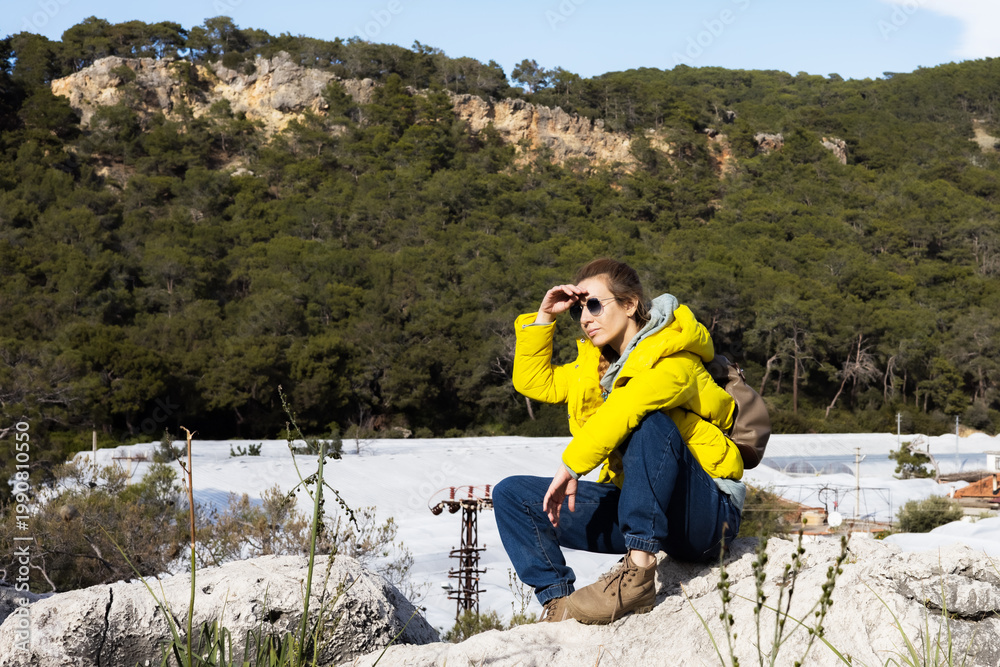 Naklejka premium Young woman in yellow jacket resting on a mountain ridge