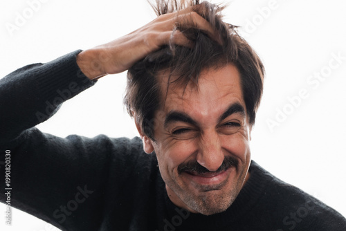 Fotografi Man expresses joy while playfully tousling his hair in bright light