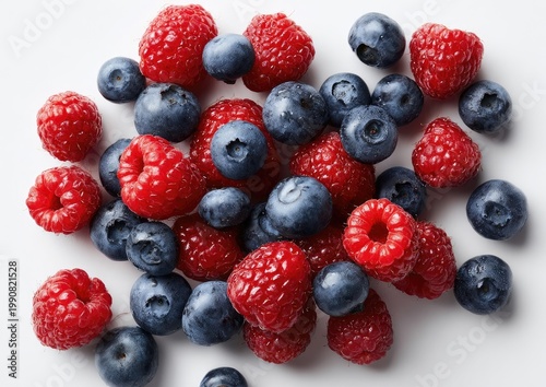 Vibrant pile of ripe raspberries and blueberries against a white background