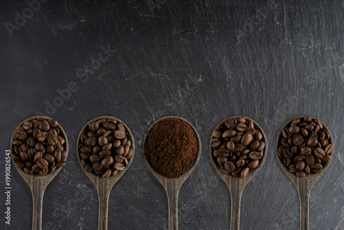 Composition avec des grains de café et du café moulu dans des cuillers en bois sur un fond en ardoise