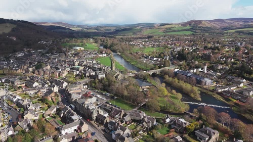 Cinematic drone flyover above the River Tweed flowing through the historic town of Peebles in the Scottish Borders landscape
