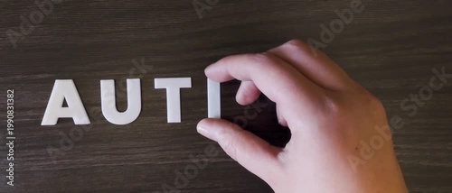 la palabra autismo escrita con letras mayúsculas blancas en un fondo oscuro (versión rápida)