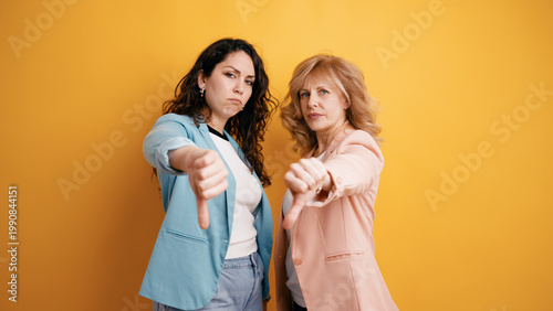 фотографія Two women expressing strong dislike, disapproval, and negation with thumbs down