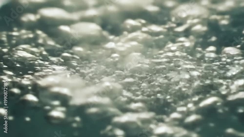 Close-up view of shimmering water surface with bubbles rising and reflecting light, showcasing the dynamic movement and texture of liquid in a natural setting