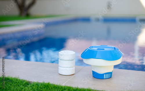 Plastic chlorine floater and stacked tablets on the edge of a swimming pool - pool maintenance concept