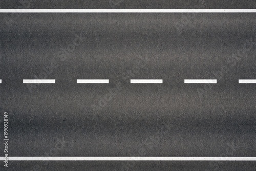 Birds eye photo of a level tar road showcasing detailed white dividing stripes