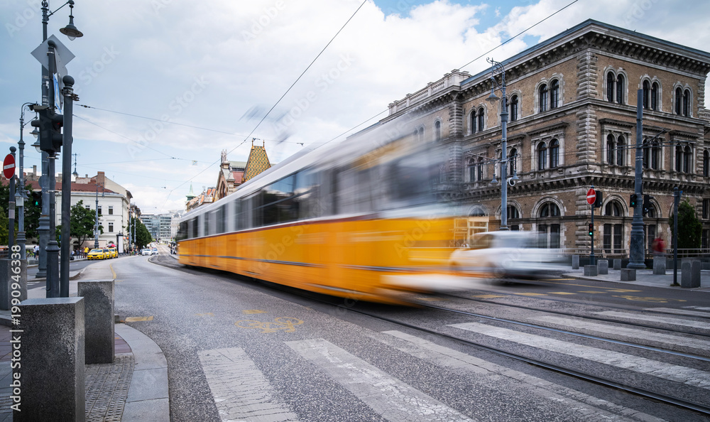 Fototapeta premium Yellow City Tram Rushes Blurred In Motion On A Central Street In Budapest
