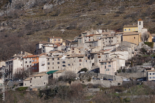 mountain landscape with snow and trees and the village of coursegoules, southern france