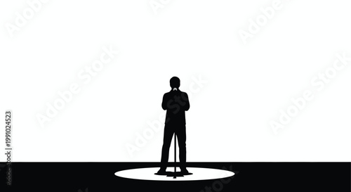 A silhouetted figure of a man standing on a brightly lit stage