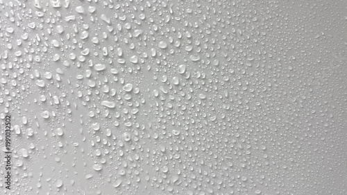 Large droplets of water drip on a light background and flow down in streams. The concept of rain, moisture, drops, moisture. High quality 4k footage