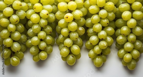 Neatly aligned fresh green grapes set on a white surface