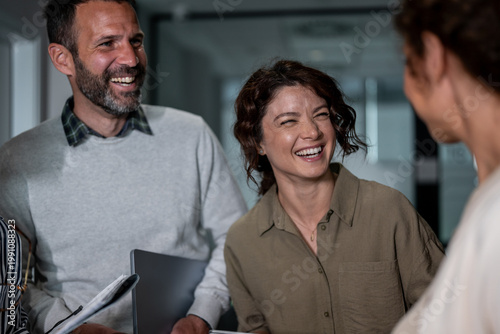 Foto Coworkers laughing cheerfully while discussing business in office