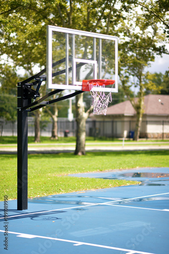Calm Neighborhood Park Illuminated By Sunlight Showcasing Basketball Net And Rowhouses. New York