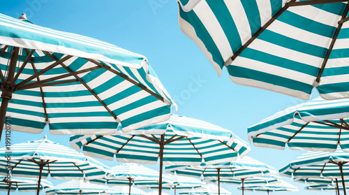 Striped beach umbrellas under blue sky summer vacation travel concept minimal sunny seaside background
