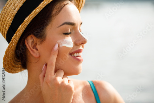 Photos Beautiful woman applying sunscreen on cheek in profile with closed eyes enjoying