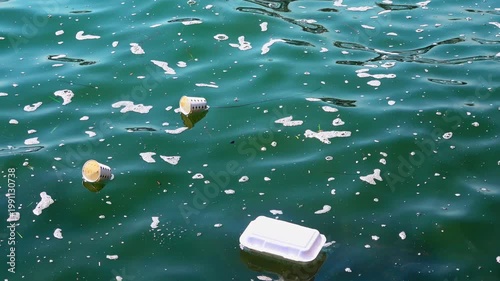 Environmental pollution with plastic cups and foam containers floating in dirty sea water. Concept of ocean waste, ecological damage, and environmental protection in coastal areas.